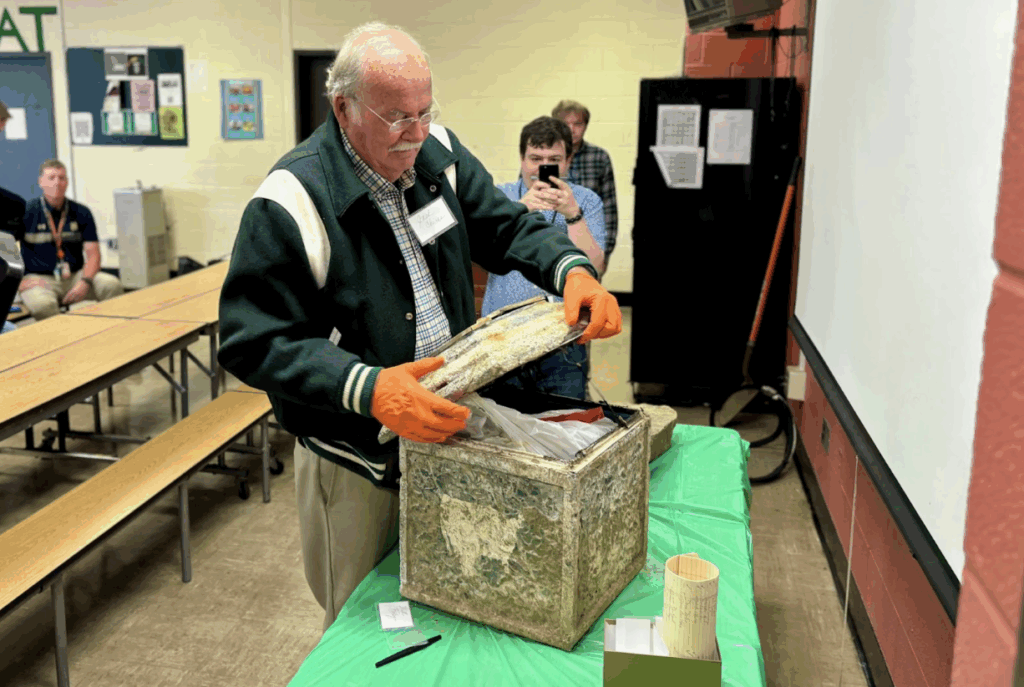 Jack Chiras, former history teacher, opens the time capsule during the ceremony